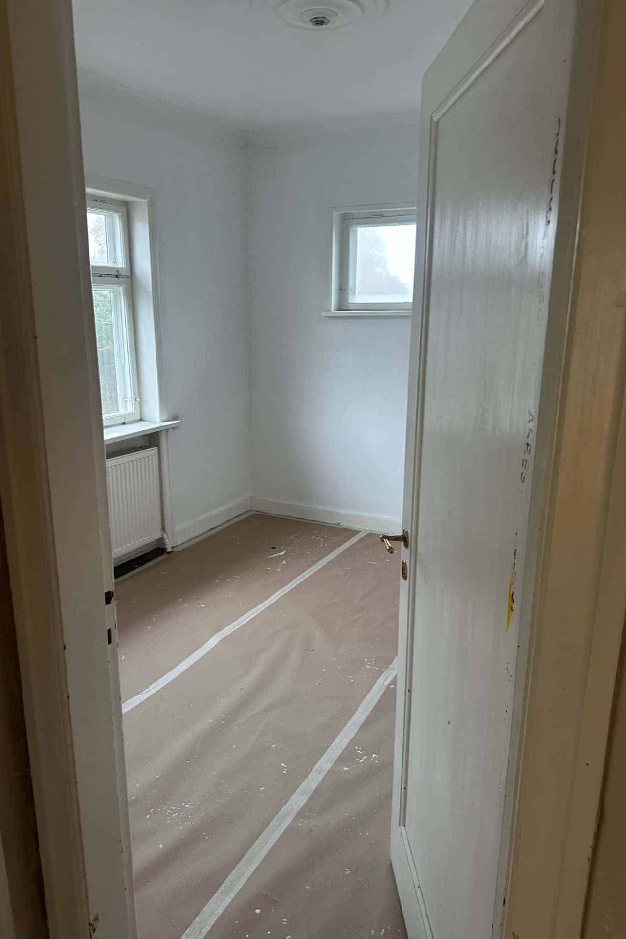 Kig ind i hvidt værelse med gulvafdækning under renovering af entreprenør Mauritzen Gruppen