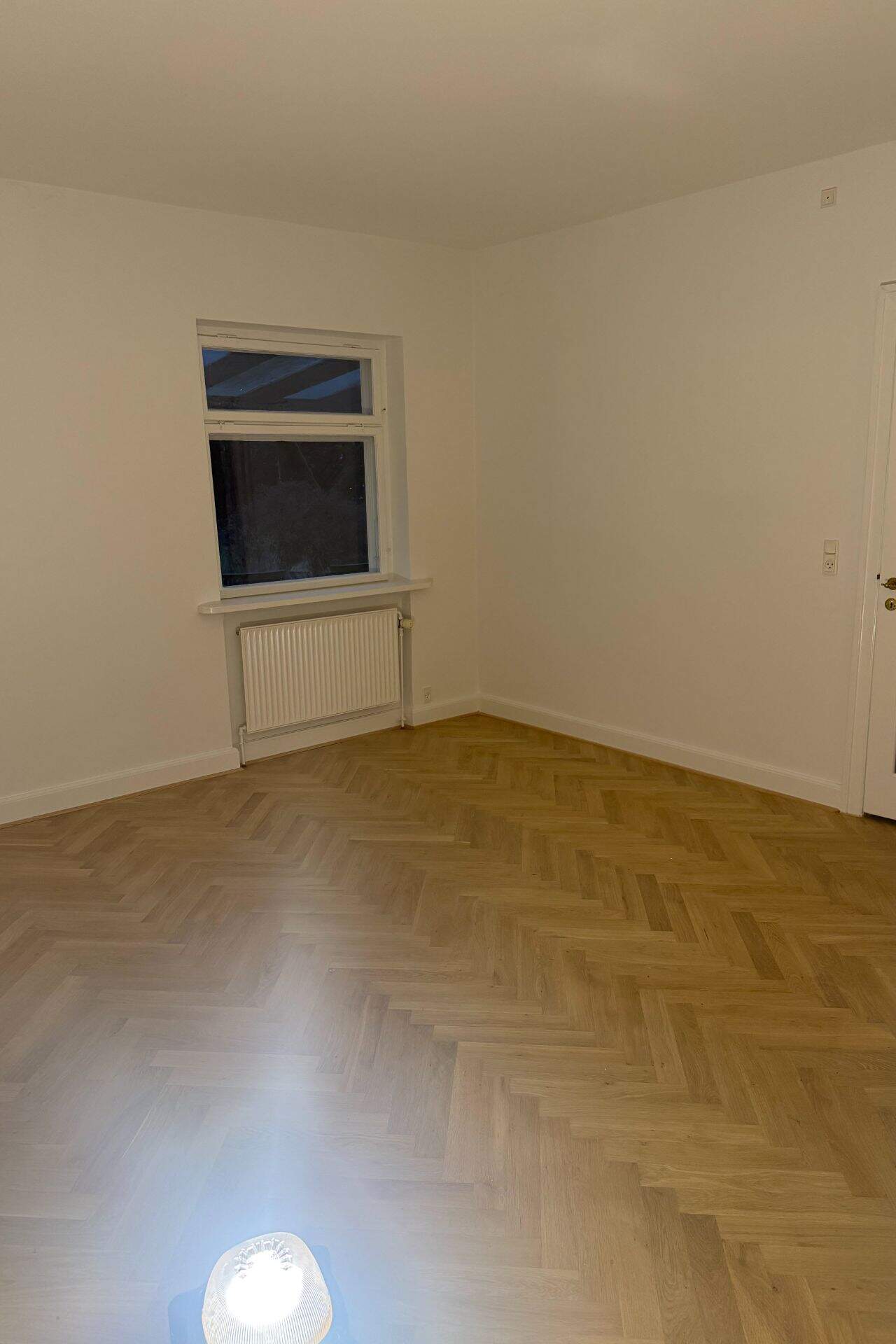 Tomt værelse med sildbensparketgulv og vindue efter renovering af entreprenør Mauritzen Gruppen